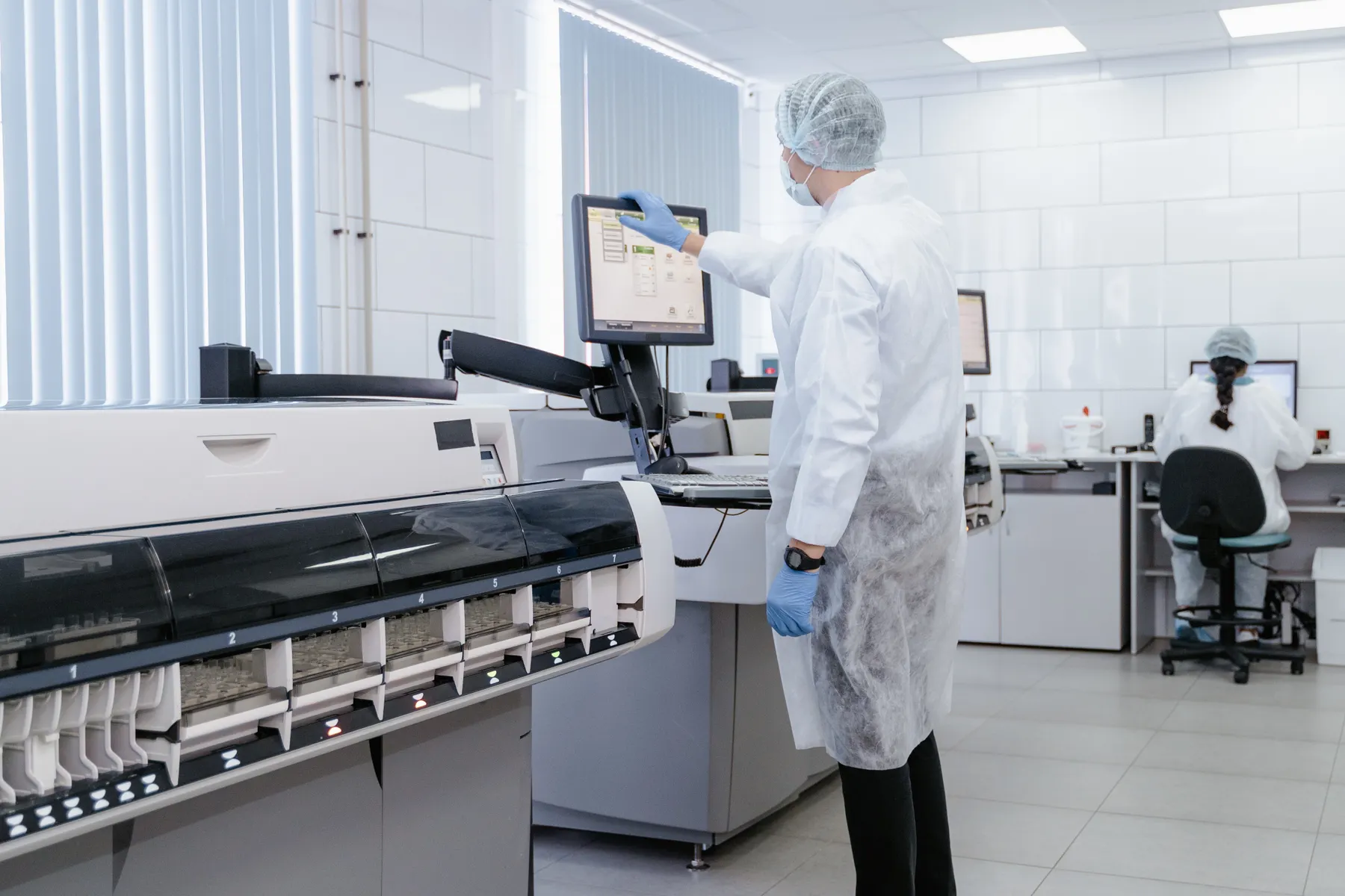 Laboratory technician operating analytical equipment in a controlled medical laboratory